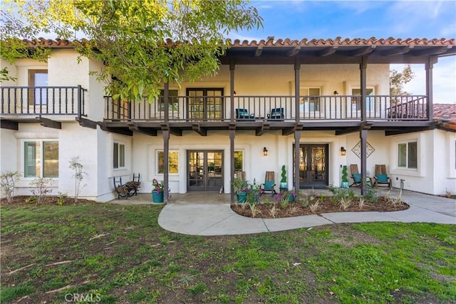 rear view of property featuring a yard, a balcony, and french doors