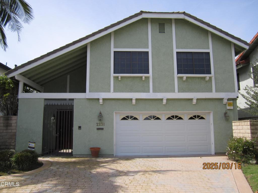 view of front of property with decorative driveway, a garage, and stucco siding