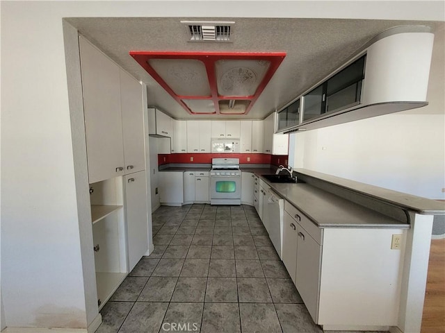 kitchen with visible vents, a sink, dark countertops, white appliances, and white cabinets