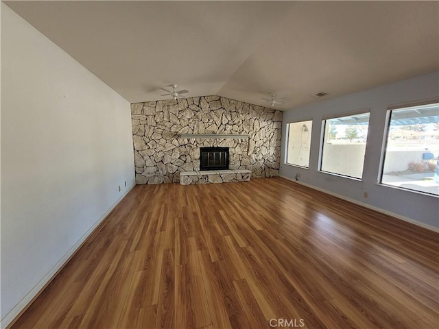 unfurnished living room featuring visible vents, vaulted ceiling, a fireplace, wood finished floors, and a ceiling fan