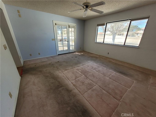 unfurnished room with a textured ceiling, carpet, and ceiling fan