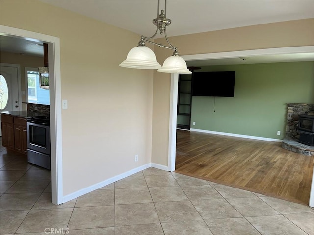 11122 Schafer Ave, Los Molinos, CA 96055 - unfurnished dining area featuring a wood stove, light tile patterned floors, and baseboards