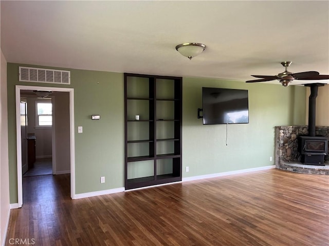 11122 Schafer Ave, Los Molinos, CA 96055 - unfurnished living room featuring a wood stove, a ceiling fan, wood finished floors, and baseboards