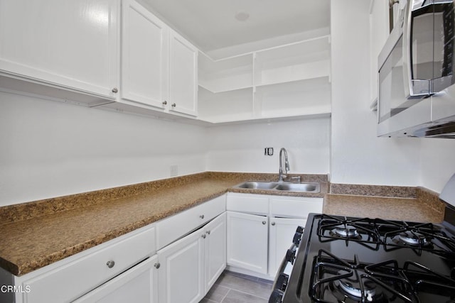 kitchen featuring open shelves, a sink, white cabinets, black range with gas stovetop, and stainless steel microwave
