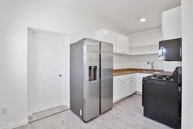kitchen with black appliances, open shelves, a sink, white cabinetry, and wood tiled floor