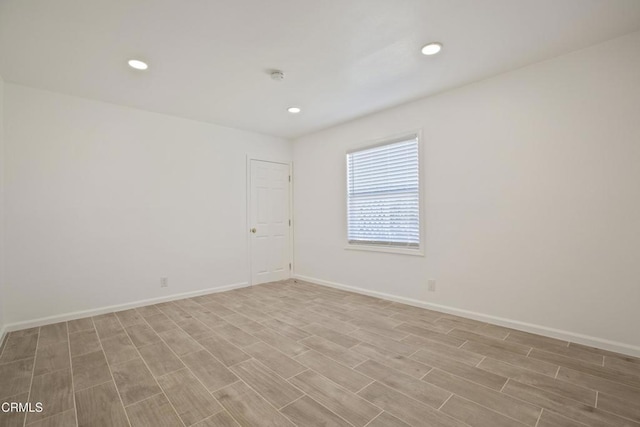 spare room featuring light wood-style flooring, recessed lighting, and baseboards