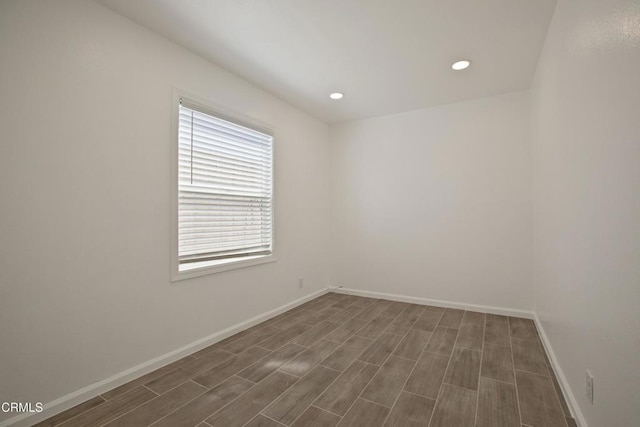 empty room with dark wood finished floors, recessed lighting, and baseboards