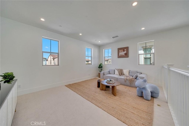 living area featuring recessed lighting, visible vents, baseboards, and light carpet