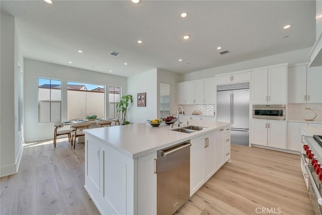 kitchen with backsplash, visible vents, a sink, and high quality appliances