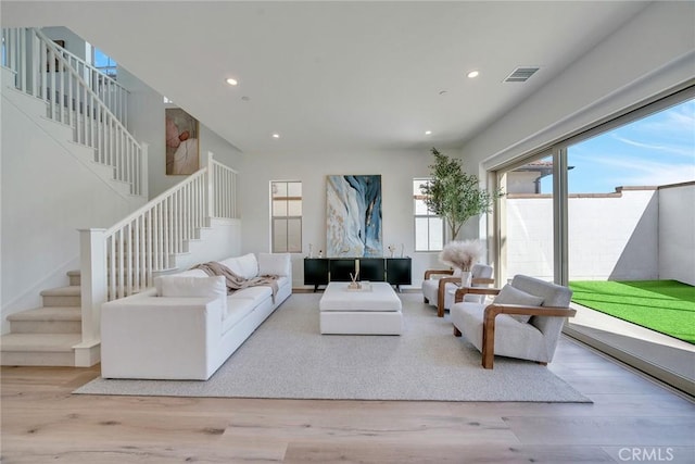living room with wood finished floors, stairs, and visible vents