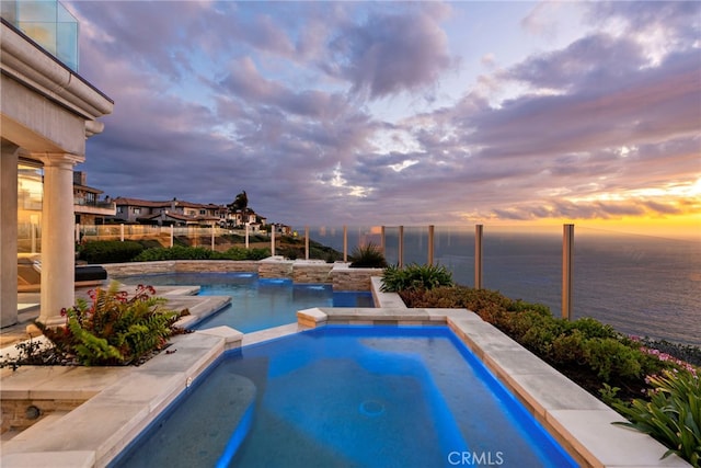31821 Monarch Crst, Laguna Niguel, CA 92677 - pool at dusk featuring a water view, a pool with connected hot tub, and fence