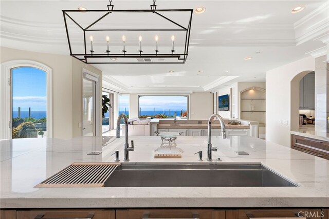 31821 Monarch Crst, Laguna Niguel, CA 92677 - kitchen featuring light stone counters, open floor plan, crown molding, arched walkways, and a raised ceiling