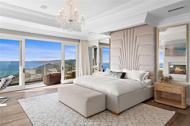 31821 Monarch Crst, Laguna Niguel, CA 92677 - bedroom with crown molding, access to exterior, a chandelier, wood finished floors, and a glass covered fireplace