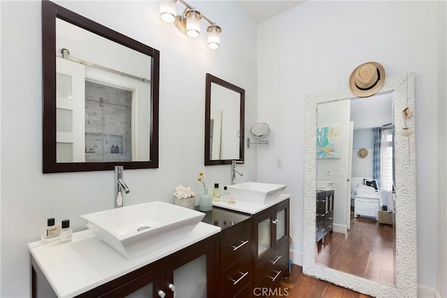 bathroom with a sink, two vanities, a stall shower, and wood finished floors