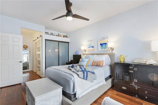 bedroom with a closet, a barn door, a ceiling fan, and wood finished floors