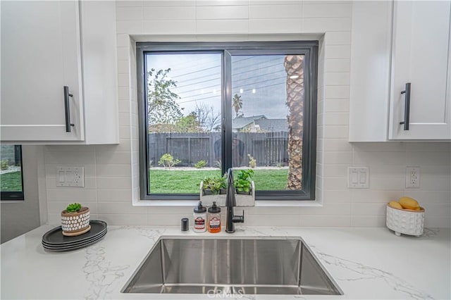 11845 Gladstone Ave, Sylmar, CA 91342 - kitchen with a sink, backsplash, white cabinets, and light stone counters