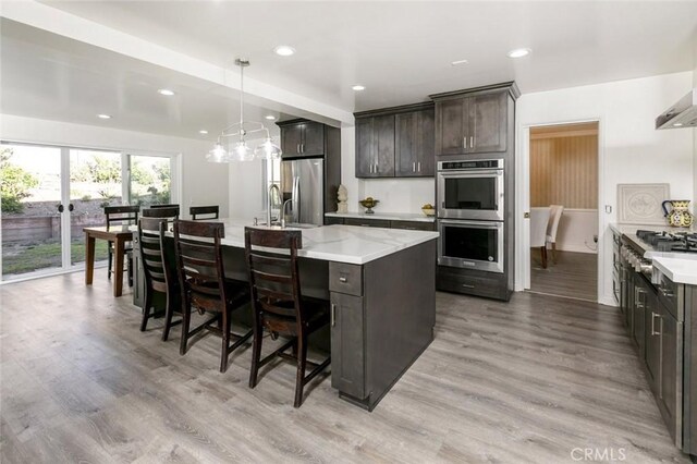 449 Fern Dell Pl, Glendora, CA 91741 - kitchen featuring stainless steel appliances, light wood-style flooring, an island with sink, a breakfast bar area, and recessed lighting
