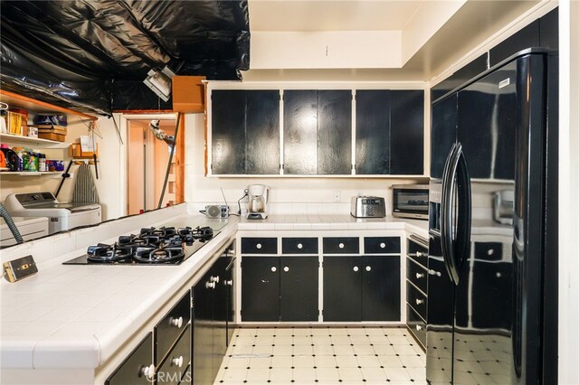 8017 Floral Ave, Los Angeles, CA 90046 - kitchen with black appliances, dark cabinetry, tile countertops, separate washer and dryer, and a toaster