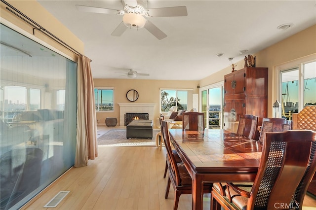 8017 Floral Ave, Los Angeles, CA 90046 - dining space with a brick fireplace, visible vents, light wood finished floors, and ceiling fan