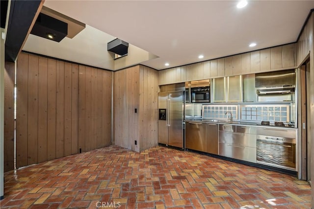 kitchen with wood walls, stainless steel appliances, and recessed lighting