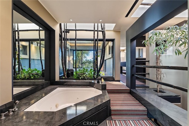 bathroom with a wealth of natural light and a tub with jets