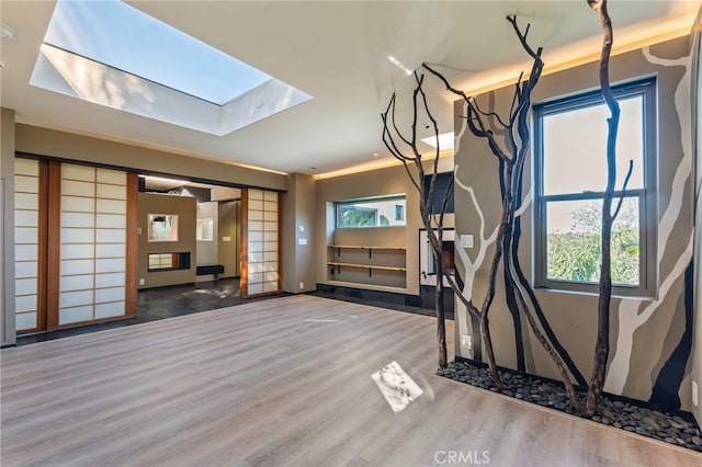 unfurnished living room with wood finished floors and a skylight