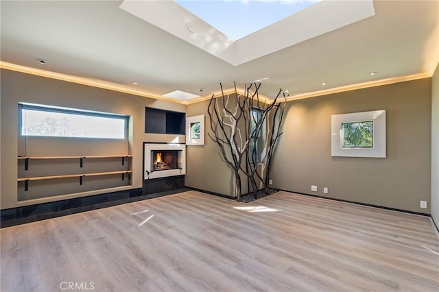 unfurnished living room featuring a wealth of natural light, crown molding, and wood finished floors