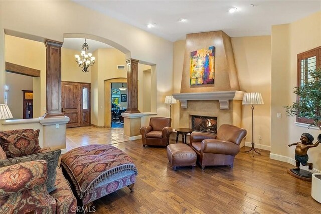 1065 Burnt Rock Way, Templeton, CA 93465 - living room featuring ornate columns, arched walkways, light wood-style floors, baseboards, and a lit fireplace
