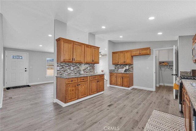 36090 Old Woman Springs Rd, Lucerne Valley, CA 92356 - kitchen with light stone counters, decorative backsplash, brown cabinetry, and vaulted ceiling