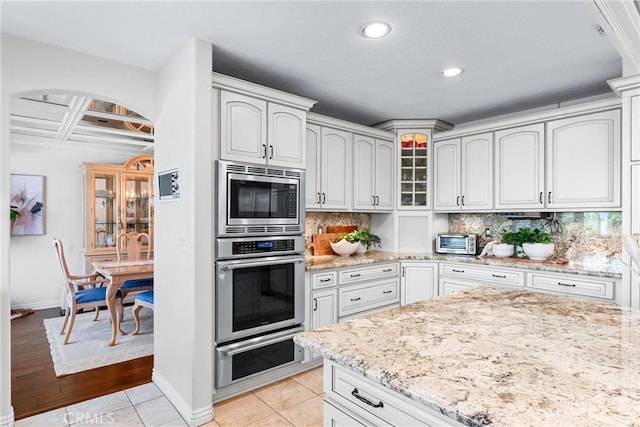 kitchen featuring stainless steel appliances, baseboards, light stone counters, decorative backsplash, and recessed lighting
