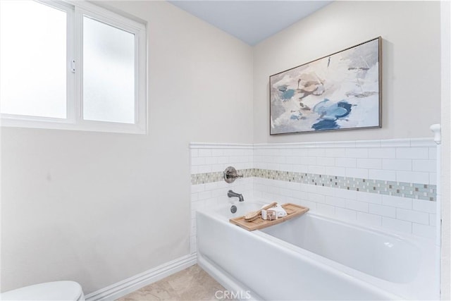 full bath featuring a garden tub, baseboards, and toilet