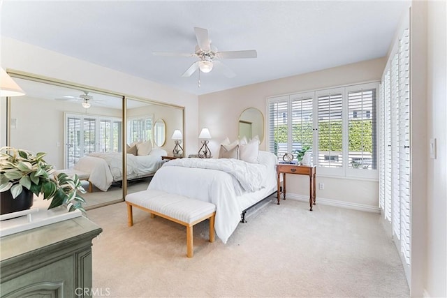 bedroom featuring light colored carpet, baseboards, ceiling fan, and a closet