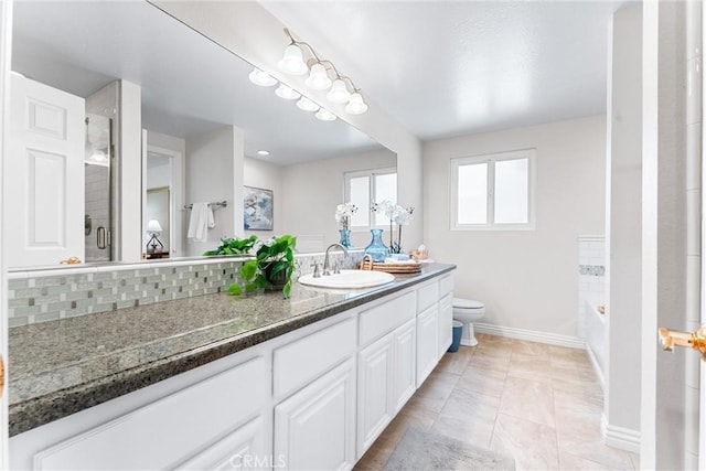 bathroom with toilet, vanity, baseboards, a shower with shower door, and backsplash