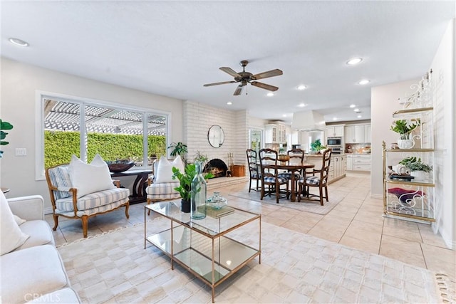 living area featuring plenty of natural light, ceiling fan, a brick fireplace, light tile patterned floors, and recessed lighting