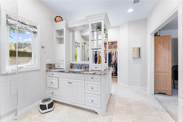 full bath with baseboards, vanity, a walk in closet, and recessed lighting