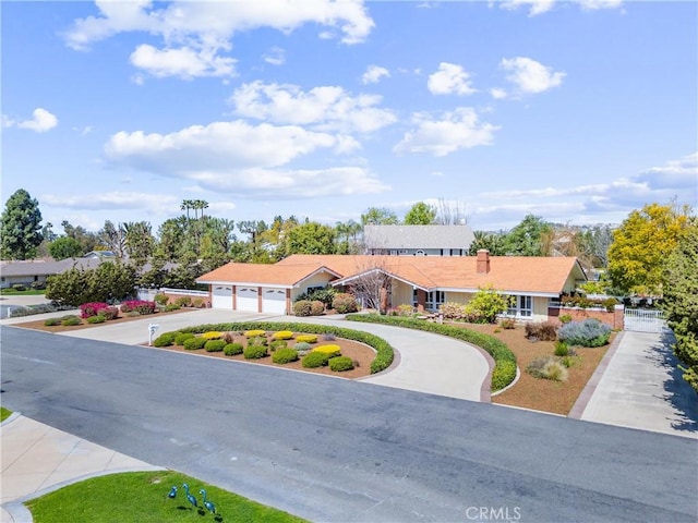 view of front of home with concrete driveway, an attached garage, and a chimney