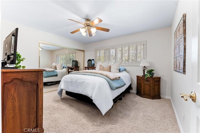 bedroom with light colored carpet, baseboards, a closet, and ceiling fan