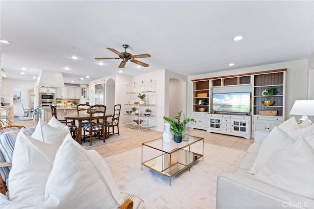 living room featuring arched walkways, a ceiling fan, recessed lighting, and light tile patterned floors