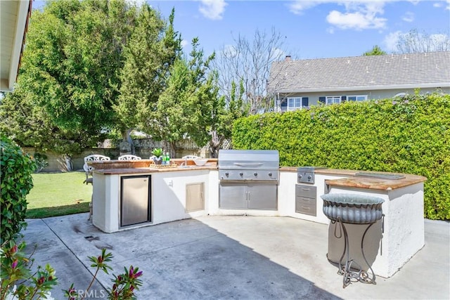 view of patio with area for grilling, a grill, and fence