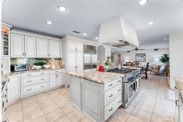 kitchen with high end appliances, custom exhaust hood, recessed lighting, decorative backsplash, and a kitchen island