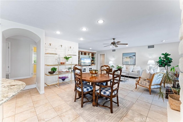 dining room with arched walkways, a ceiling fan, recessed lighting, light tile patterned floors, and baseboards