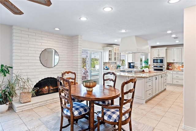 dining area with light tile patterned floors, a fireplace, and recessed lighting