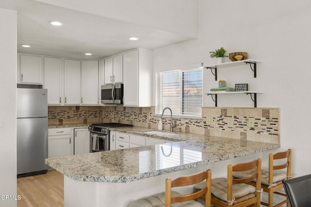 5125 W Wooley Rd Unit 5, Oxnard, CA 93035 - kitchen with stainless steel appliances, a peninsula, white cabinets, decorative backsplash, and recessed lighting