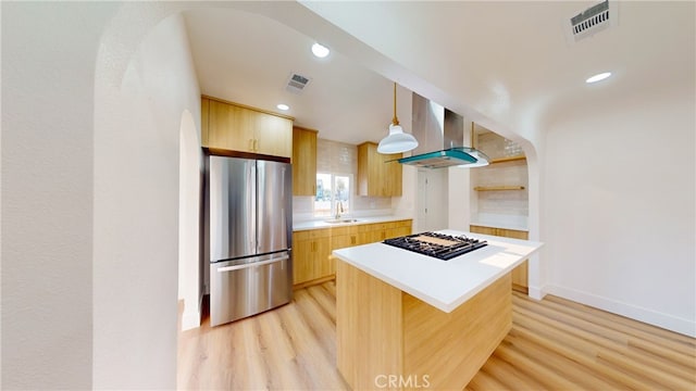 kitchen with visible vents, wall chimney range hood, black gas cooktop, freestanding refrigerator, and a sink