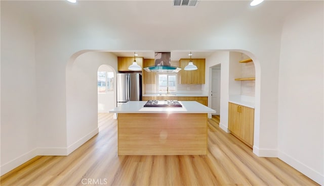 kitchen featuring a kitchen island, appliances with stainless steel finishes, island range hood, arched walkways, and a sink