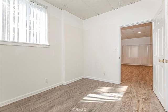 spare room featuring wood finished floors, baseboards, and a paneled ceiling
