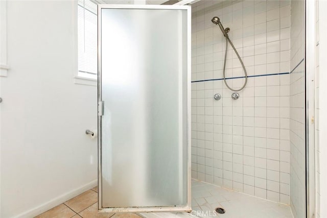 bathroom with tile patterned flooring, a shower stall, and baseboards