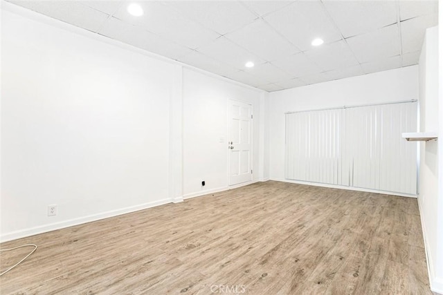 spare room featuring recessed lighting, a drop ceiling, baseboards, and wood finished floors