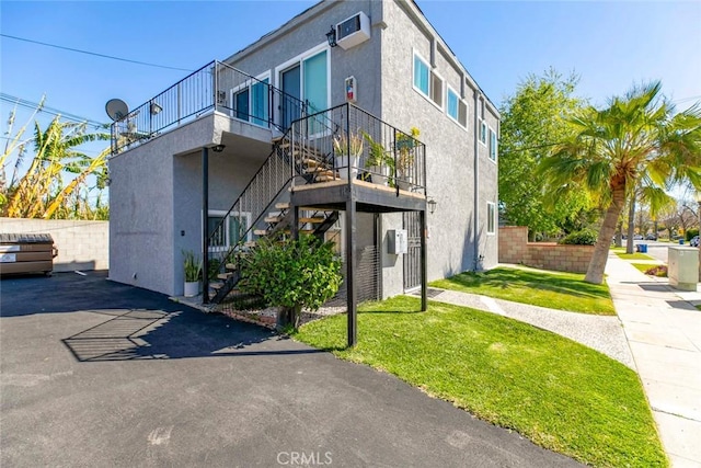 view of home's exterior featuring stairway, stucco siding, and a lawn