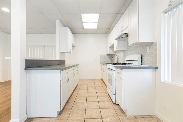 kitchen featuring white range with gas cooktop, tasteful backsplash, light tile patterned flooring, and white cabinets